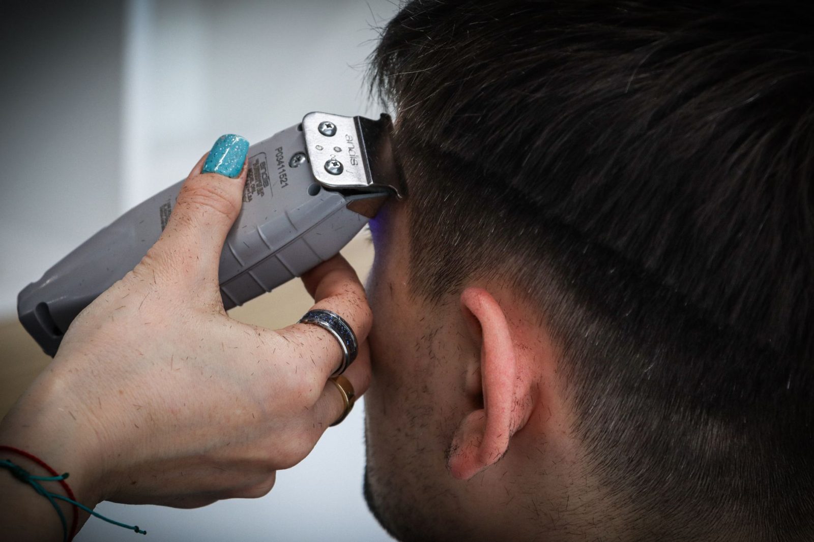 Detailed view of a haircut in progress with electric clippers and the stylist's hand guiding the cut
