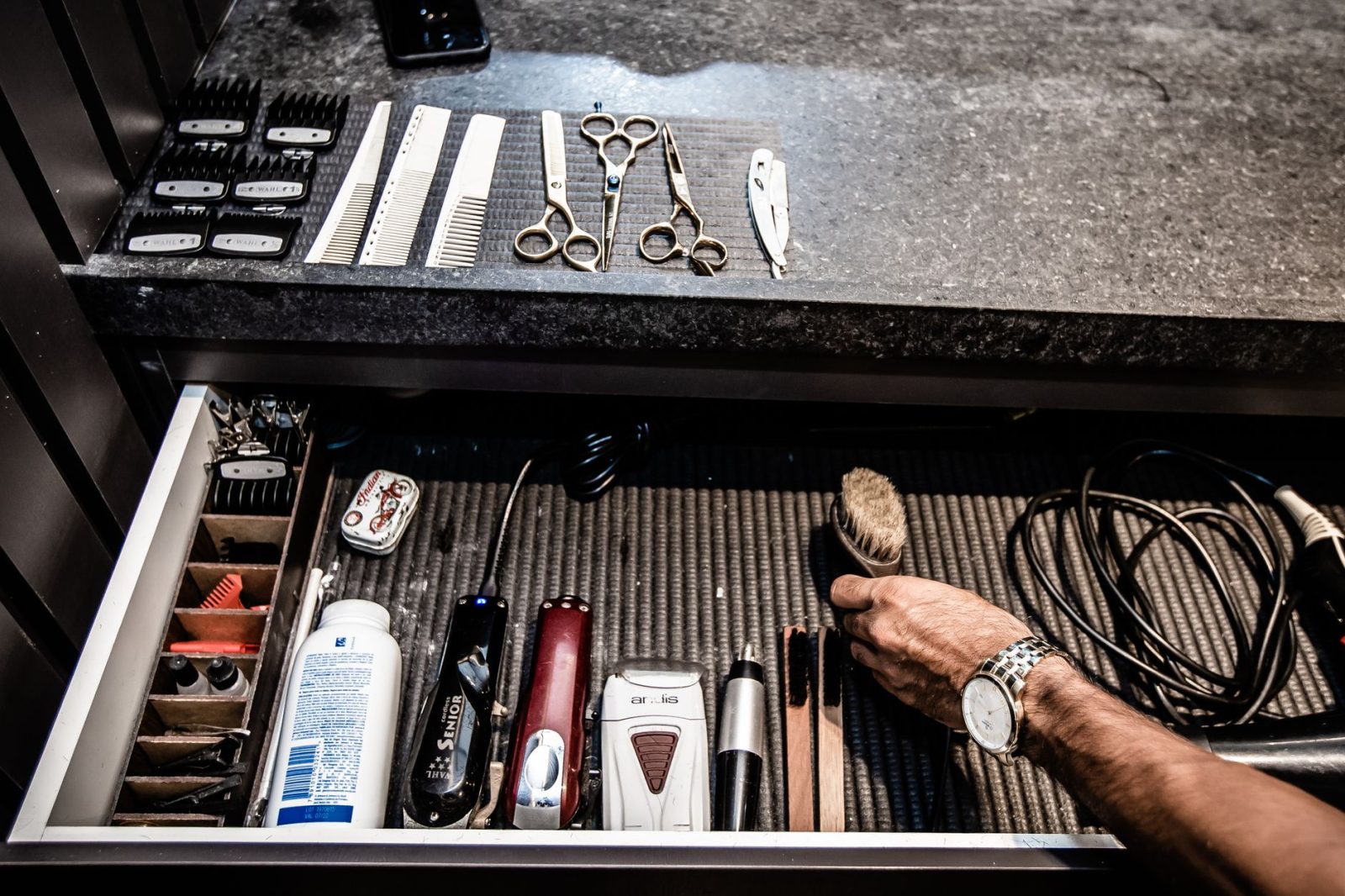 A neatly organized drawer of barber tools and accessories at a barber station