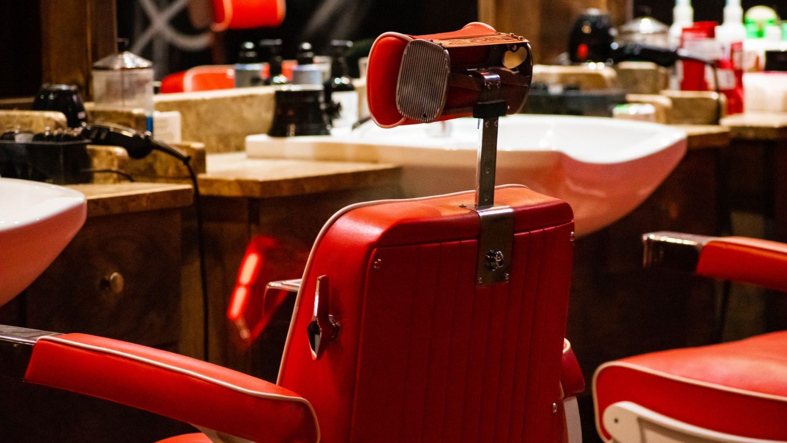 A red leather barber chair in front of the wash basins