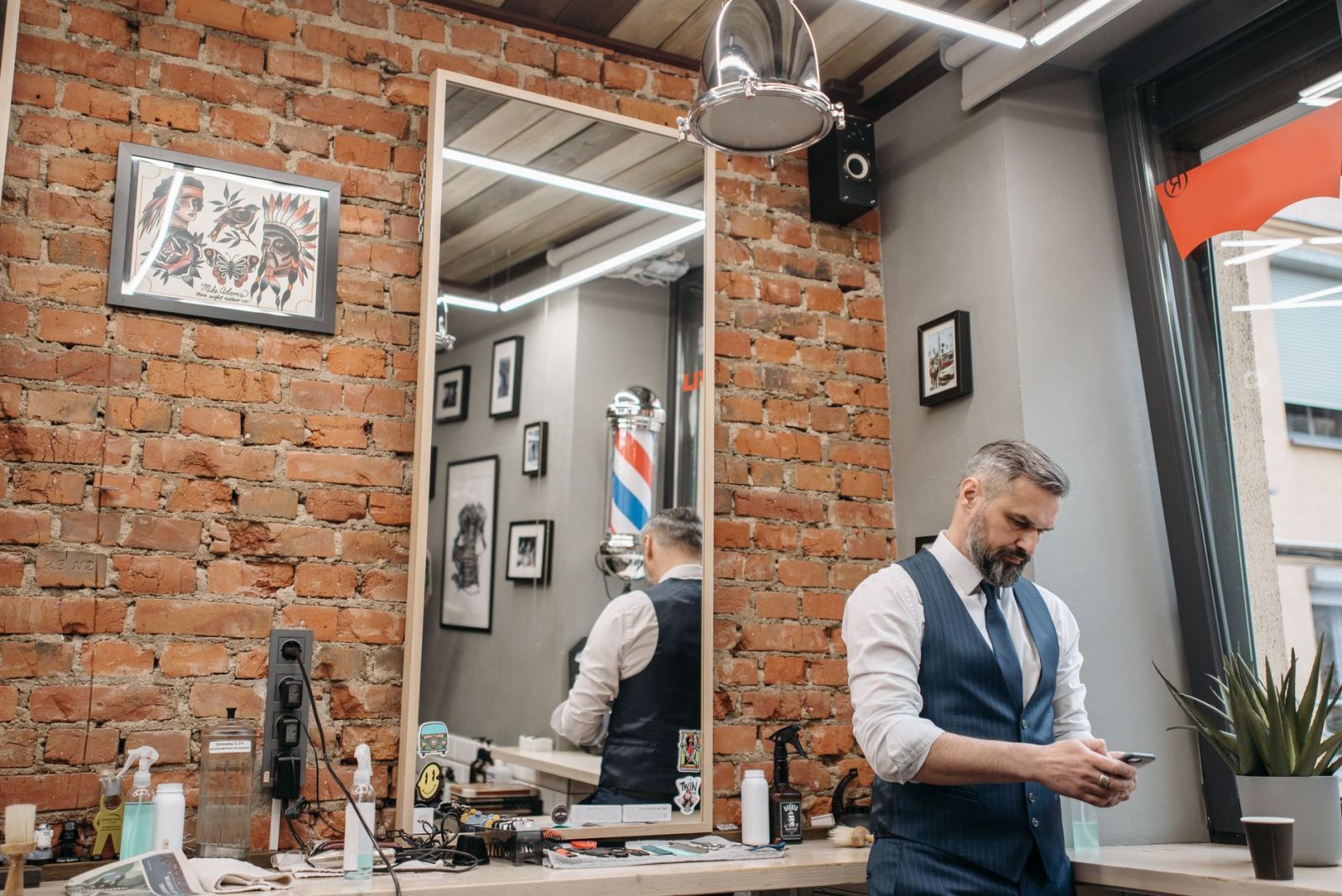 A barber at his station by the brick wall, ready for the next client