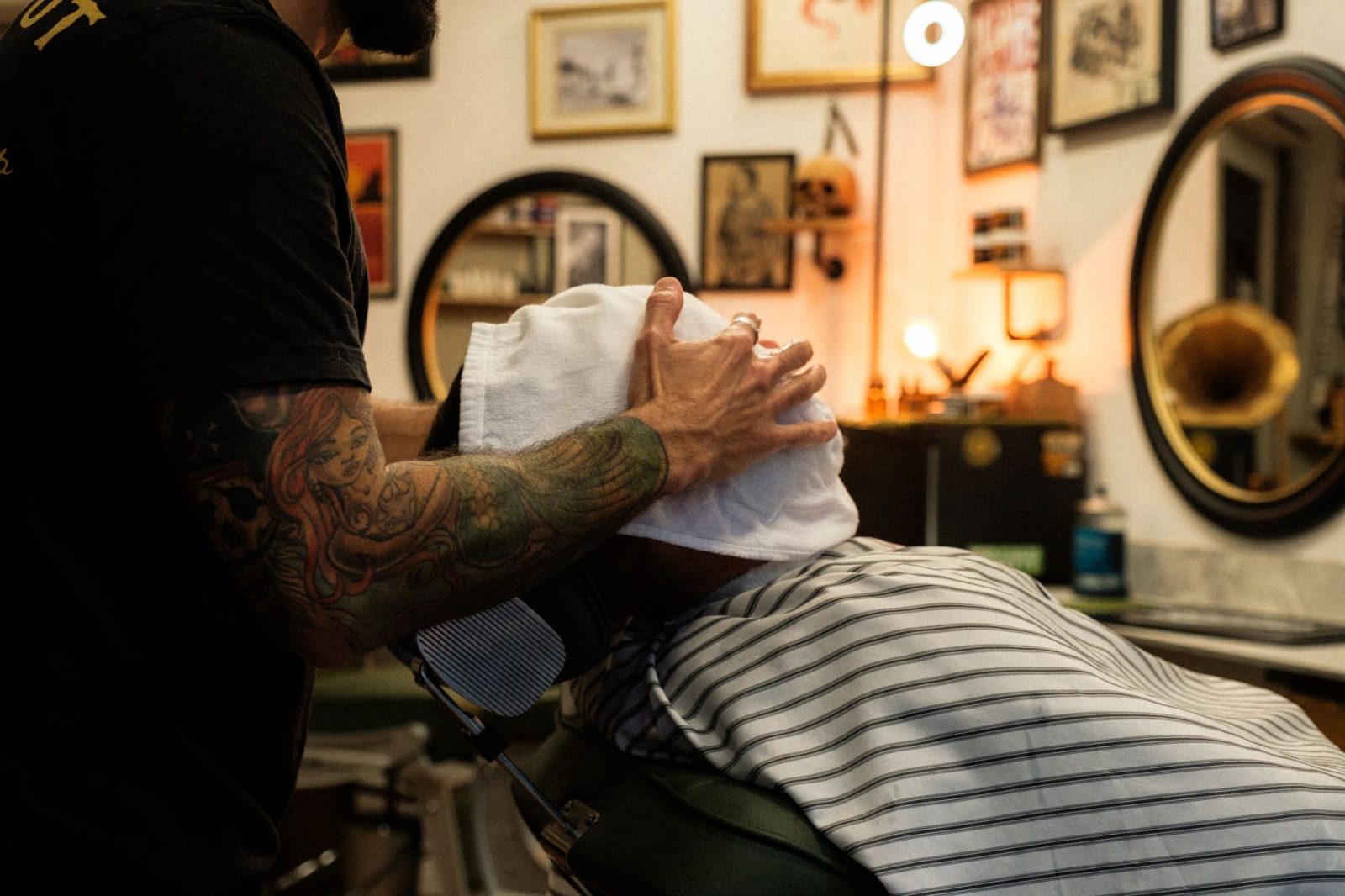 A barber wraps a client in a hot towel before a shave